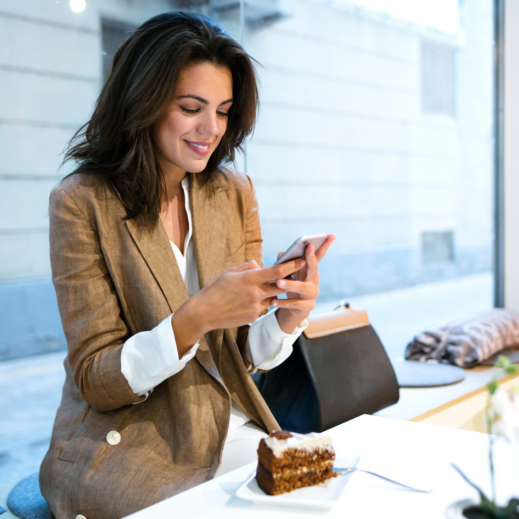 Shot of happy young businesswoman texting with her mobile phone in a coffee shop.